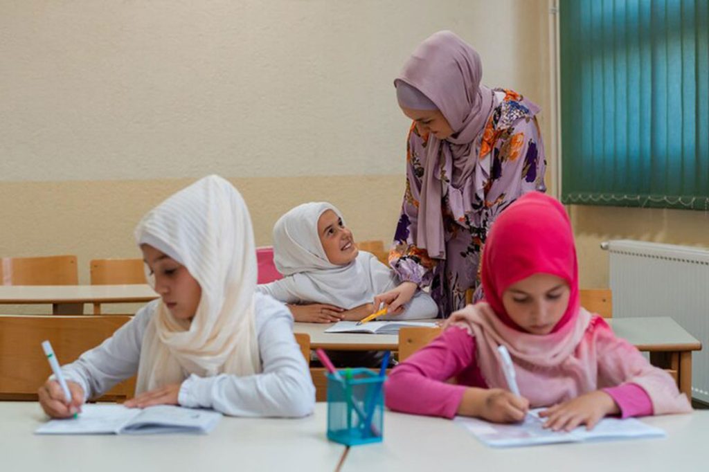 female-hijab-muslim-teacher-helps-school-children-finish-lesson-classroom 606562-291